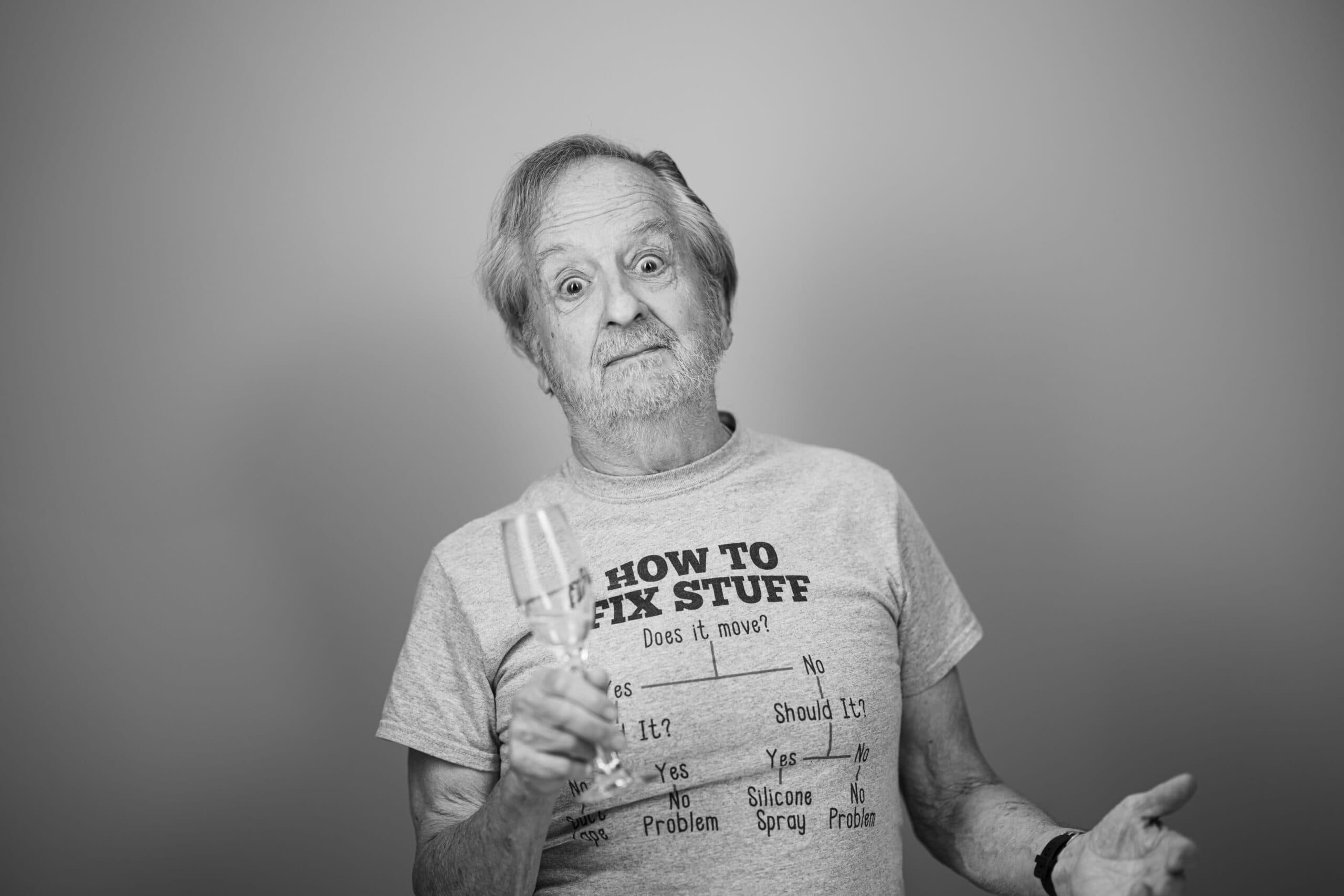 Black and white portrait of a Holladay Park Plaza resident holding a glass of champagne and making a silly face.